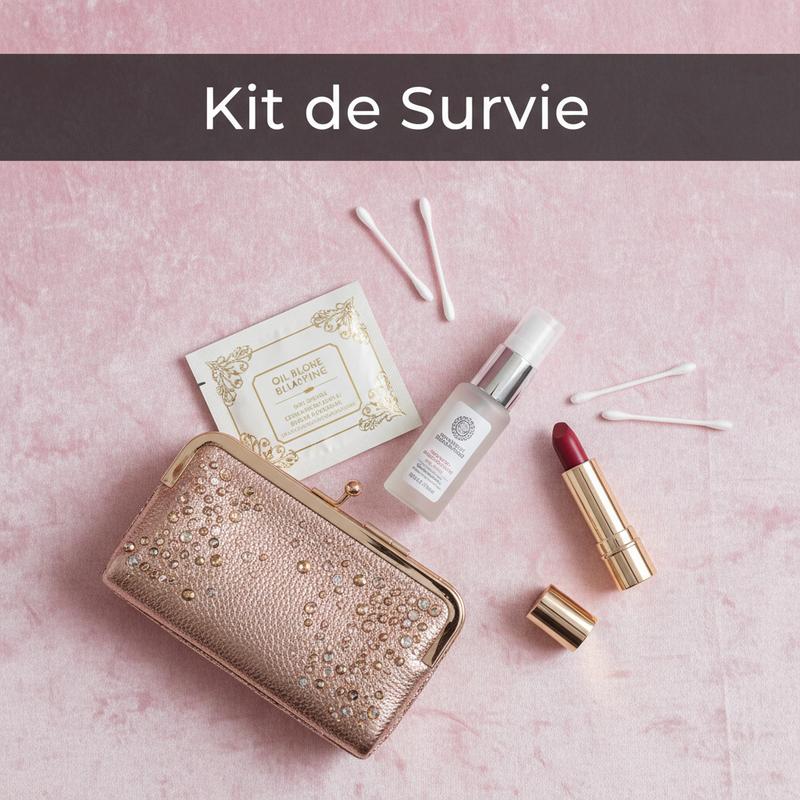 Pochette de soirée chic disposée sur du velours rose pastel avec rouge à lèvres et accessoires de maquillage, texte Kit de Survie.