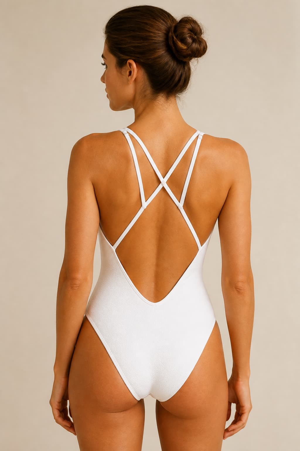 Vue de dos d’un maillot de bain blanc mettant en valeur des liens croisés au niveau du dos, avec une coiffure relevée dégageant la nuque.